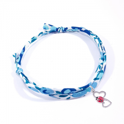 bracelet en tissu liberty bleu clair avec pendentif coccinelle posée sur deux cœurs en argent