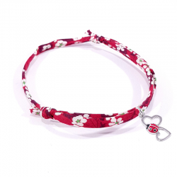 bracelet en tissu liberty rouge avec pendentif coccinelle posée sur deux cœurs en argent